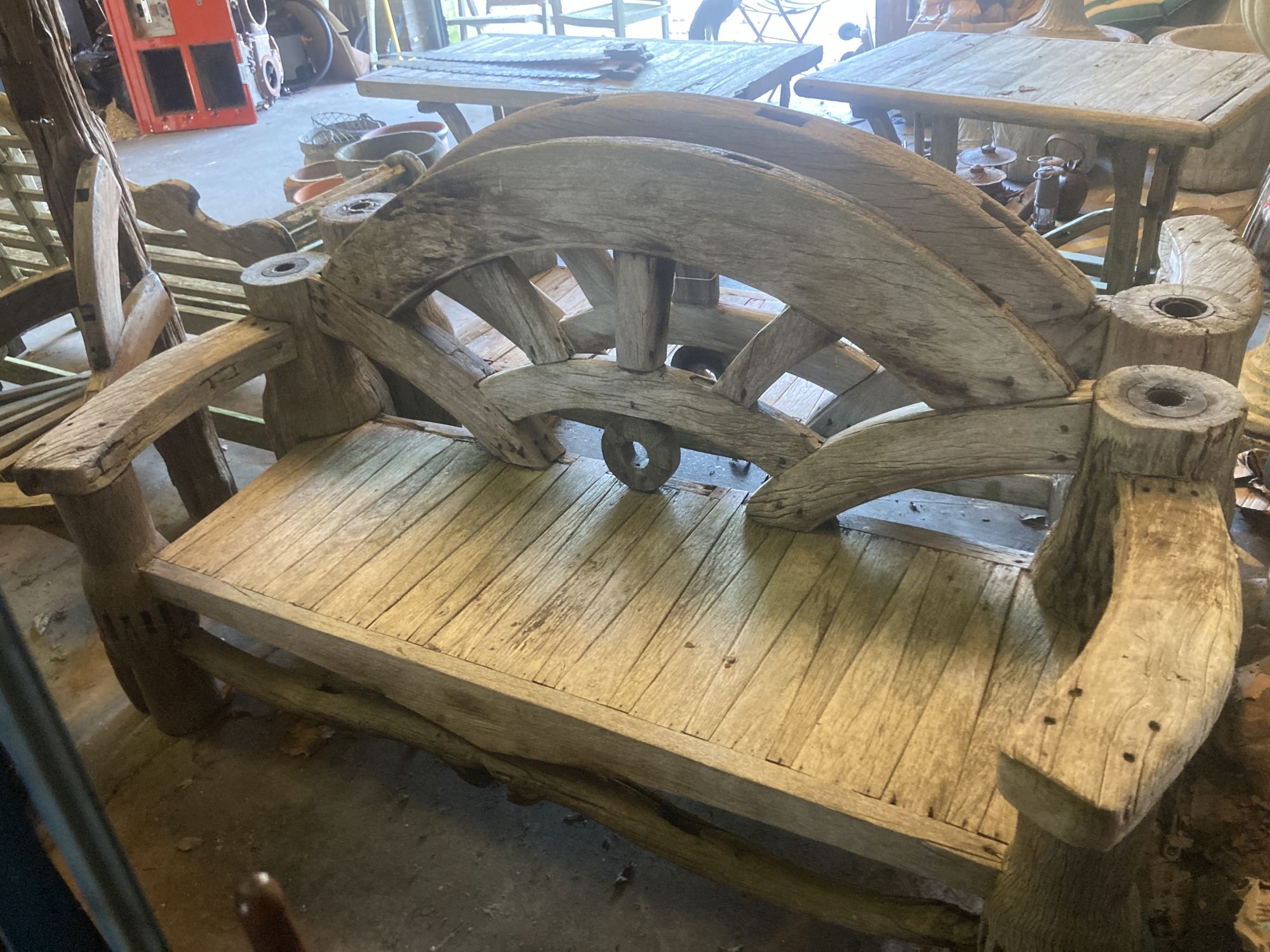 A pair of weathered hardwood cartwheel and hub garden benches, width 184cm depth 75cm height 105cm